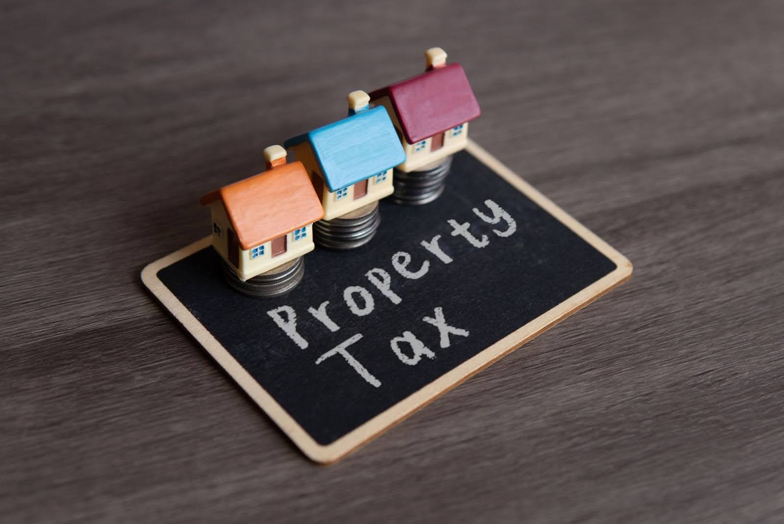 Toy house and chalkboard with text PROPERTY TAX. 